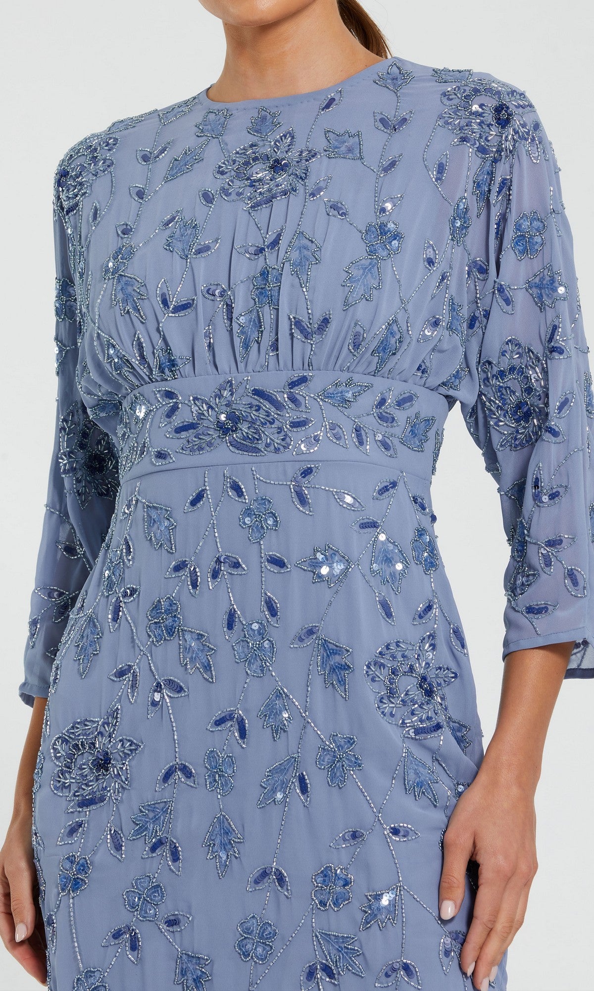 A person wearing the Mac Duggal 94141 Midi Party Dress, which features a light blue hue, intricate floral embroidery with sequin accents, three-quarter sleeves, a fitted waist, and flowy fabric. Only the upper body is visible.